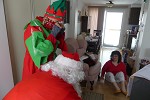 Santa Claus and his elf visiting a group of people